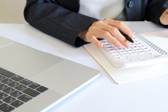 パソコンと電卓を使っている手元
