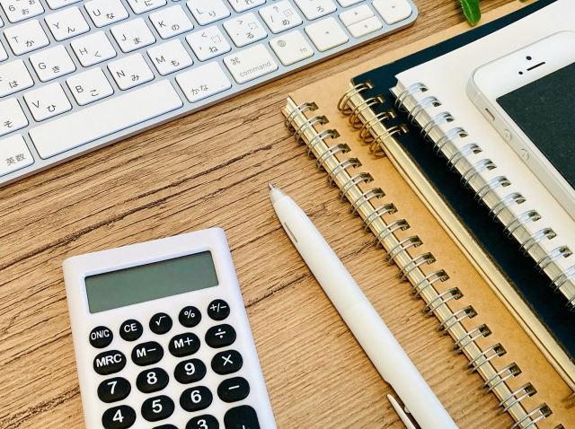 机の上の電卓、ノート、PC