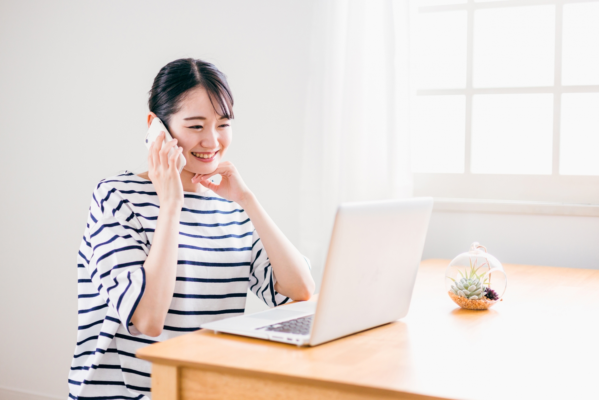 パソコンを見ながら電話をする女性